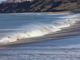 Ocean waves crashing on a beach with cliffs in the background at South Villa Sandsend near Whitby