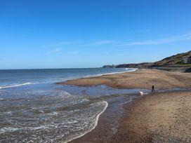 A beach with a person walking a dog at South Villa Sandsend near Whitby