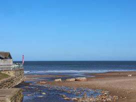A beach with a building and flag at South Villa in Sandsend near Whitby