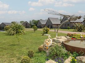 An outdoor area with houses, a sculpture, and a pond at James Ville Marina Lodge 13 in Brigg