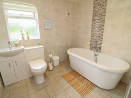 A bathroom with a bathtub, toilet, sink, and vanity unit at James Ville Marina Lodge 14 in Brigg