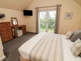 A bedroom with a bed, dresser, mirror, and television at James Ville Marina Lodge 14, Brigg