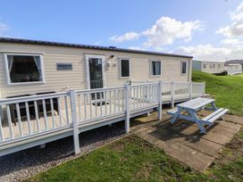 A caravan with a deck and picnic table at Dunes View in Prestatyn