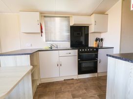 A kitchen with cabinets and a stove at Dunes View in Prestatyn