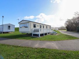 A mobile home with a deck and table at Dunes View in Prestatyn