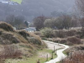 A pathway through dunes with bushes and mobile homes at Dunes View in Prestatyn