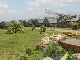 An outdoor area with houses, a pond, and a dragonfly sculpture at James Ville Marina Lodge 10 in Brigg