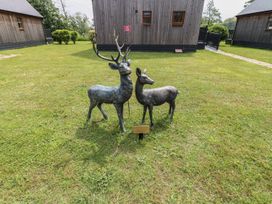 Deer sculptures on grass with wooden buildings at James Ville Marina Lodge 10 in Brigg
