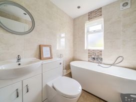 A bathroom with a bathtub, toilet, sink, and mirror at James Ville Marina Lodge 10 in Brigg