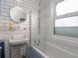 A bathroom with a bathtub, sink, mirror, and shower at Apartment 2 in Scarborough