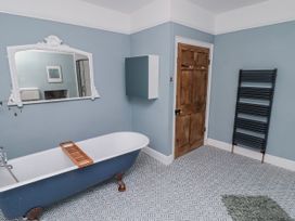 A bathroom with a bathtub and mirror at The Secret Garden in Narberth