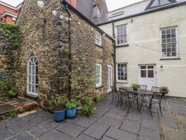An outdoor area with a stone wall and a table with chairs at The Secret Garden in Narberth