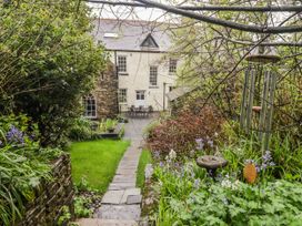 A garden with a pathway leading to a house with a table and chairs at The Secret Garden in Narberth