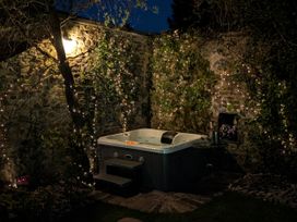 A hot tub with steps and fairy lights in the garden at The Secret Garden in Narberth