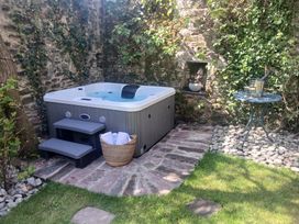 A garden with a hot tub and small table at The Secret Garden in Narberth