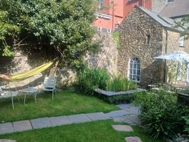 A garden with a hammock, chairs, and a stone wall at The Secret Garden in Narberth