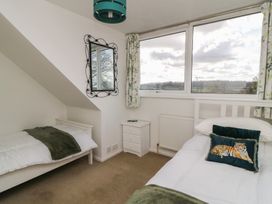 A bedroom with two beds and a mirror at 11 Berry Close in Painswick