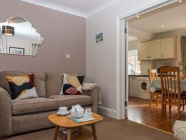 A living room with a sofa and coffee table leading to a kitchen at 16 Elmbank Gardens Paignton