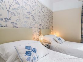 A bedroom with two beds and a floral wallpaper at 16 Elmbank Gardens Paignton