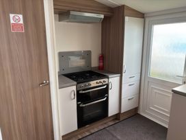 A kitchen with a gas stove and cabinets at Harlyn Hideaway (Swift Barritz) Padstow
