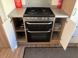 A kitchen with a stove and storage under countertops at Harlyn Hideaway (Swift Barritz) Padstow