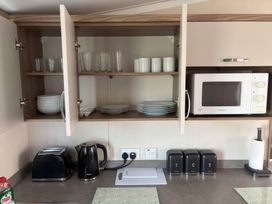 A kitchen with plates and glasses in cabinets at Harlyn Hideaway (Swift Barritz) Padstow