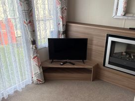 A living room with a television and electric fireplace at Harlyn Hideaway (Swift Barritz) Padstow