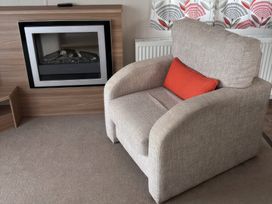 A living room with an armchair and a fireplace at Harlyn Hideaway (Swift Barritz) Padstow