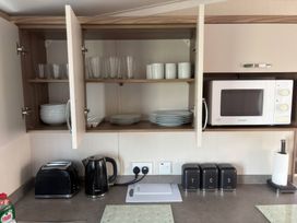 A kitchen with cabinets containing dishes and glasses at Harlyn Hideaway (Swift Barritz) Padstow