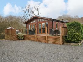 A wooden lodge with decking and outdoor seating at Waters Edge Lodge in Windermere