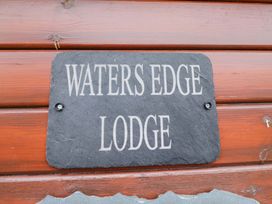 A sign displaying 'WATERS EDGE LODGE' on a wooden structure at Waters Edge Lodge in Windermere