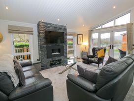 A living room with a television and fireplace at Waters Edge Lodge in Windermere