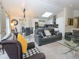 A living room with a sofa, armchair, and dining table at Waters Edge Lodge in Windermere