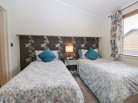 A bedroom with two single beds and a bedside table at Waters Edge Lodge in Windermere