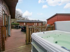 A hot tub on a deck with outdoor furniture at Waters Edge Lodge Windermere