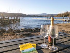 A table with drinks and a guidebook near a lake at Waters Edge Lodge in Windermere