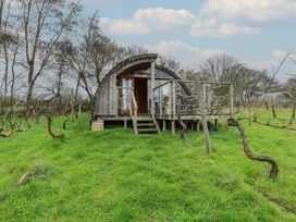 A wooden cabin with a deck surrounded by grass and vines at Vine View near Halesworth