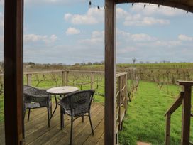A deck with chairs and a table overlooking a vineyard at Vine View near Halesworth