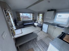 A living room with a sofa, table, and kitchen area at N5 in Ilfracombe