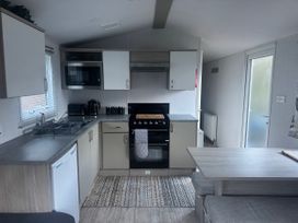 A kitchen with appliances and dining table at N5 in Ilfracombe
