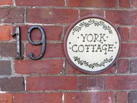 A house number and sign on a brick wall at York Cottage in Southwold