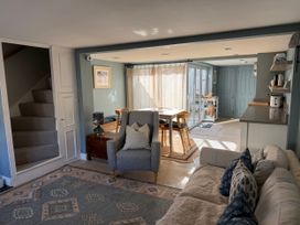 A living room with stairs, a sofa, and a kitchen counter at York Cottage Southwold