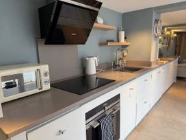 A kitchen with microwave, kettle, stove, and sink at York Cottage Southwold