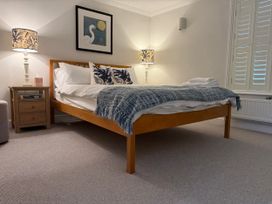A bedroom with a bed, nightstand, and lamps at York Cottage Southwold