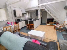 A living room with a sofa and kitchen area at Brewery Cottage