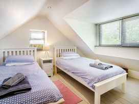 A bedroom with two beds and a nightstand at Brewery Cottage