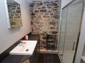A bathroom with a sink, mirror, shower and towel rack at Brewery Cottage