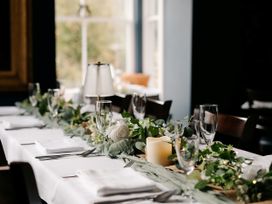 A dining table set with glasses and greenery at Picton House near St Clears