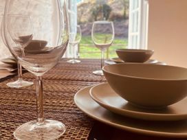 A dining table set with plates and glasses at Coach House near St Clears