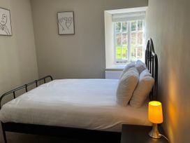 A bedroom with a bed, lamp, and window at Coach House near St Clears